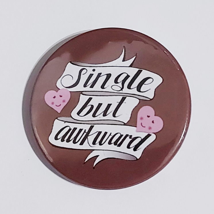 Badge with a brown background that reads "Single but awkward"